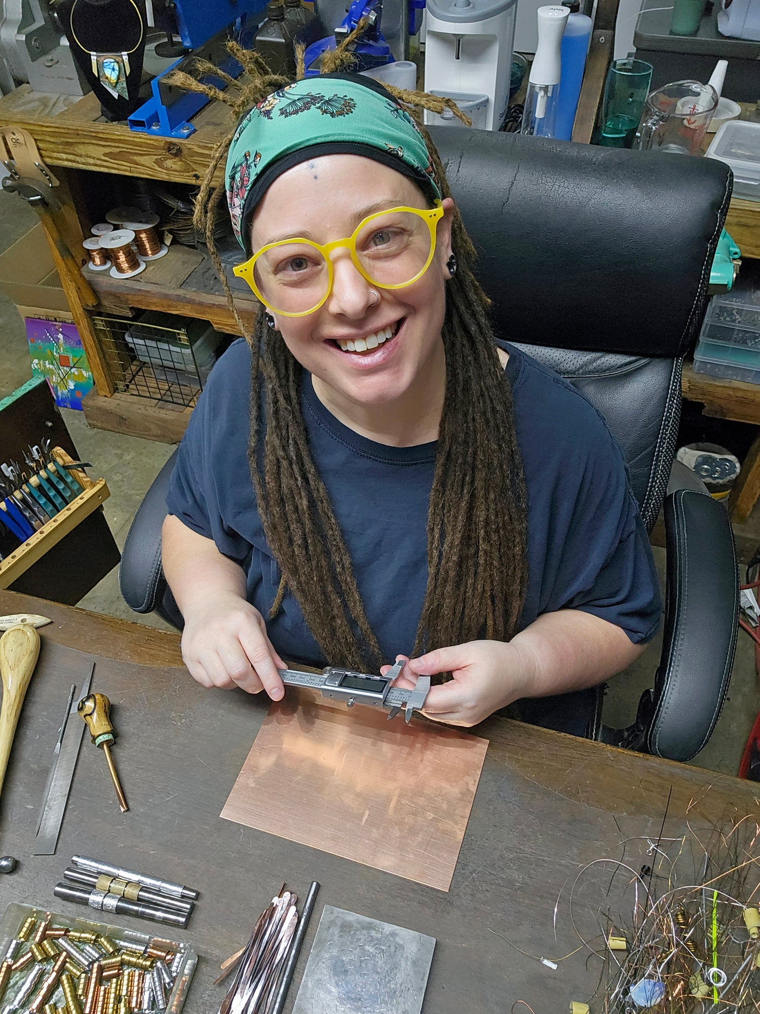 Artist and owner of Heatherfish sitting at a work bench working on heatherfish jewelry.