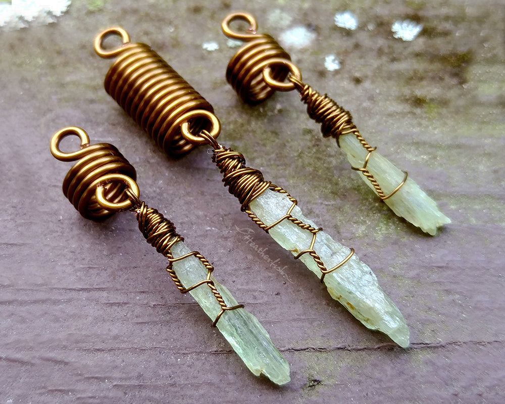 A set of 3 kyanite hair beads on a brown wood background.