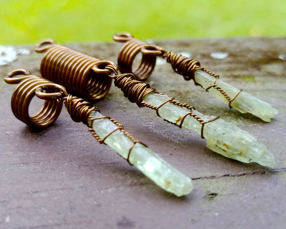 A set of 3 kyanite hair beads on a brown wood background.
