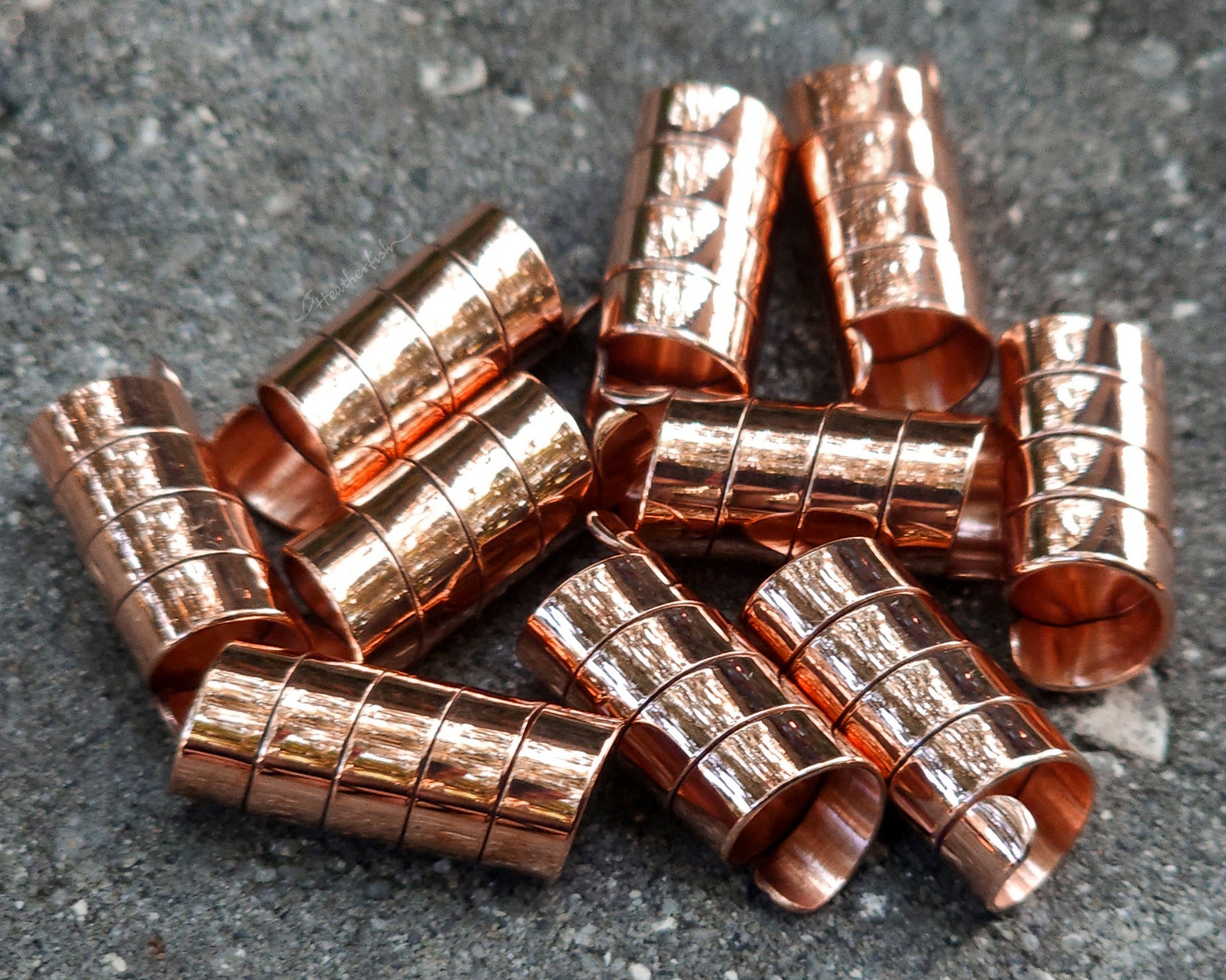 Set of 10 copper hair cuffs on a concrete surface