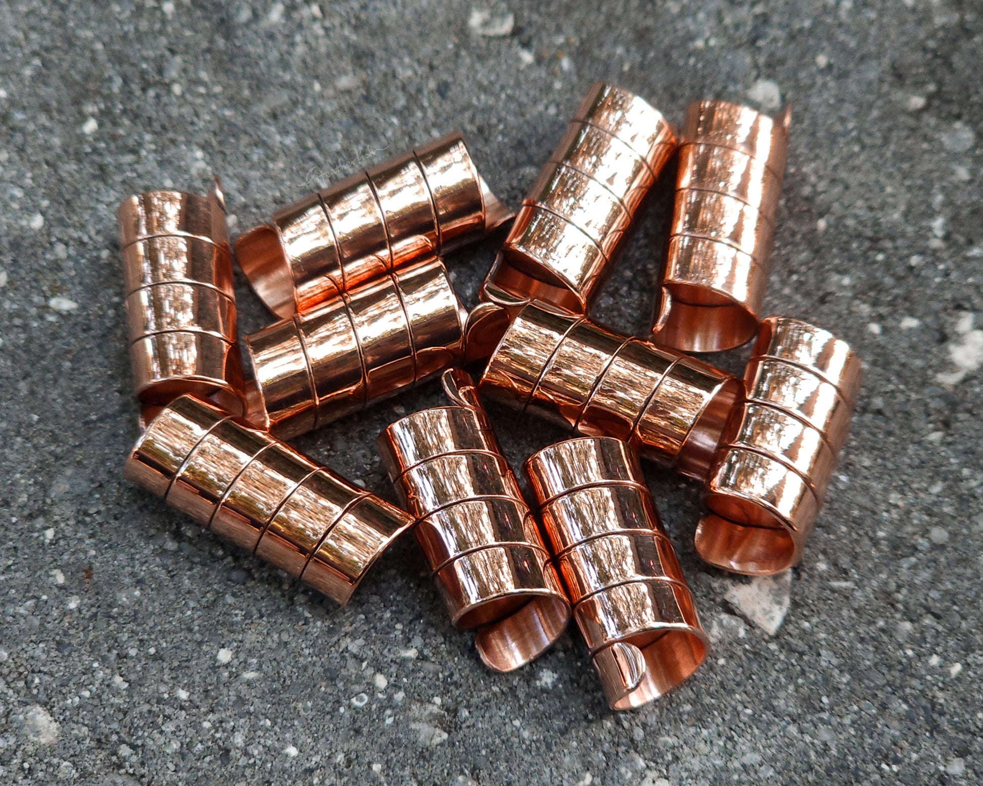 Set of 10 copper loc jewels on a concrete surface
