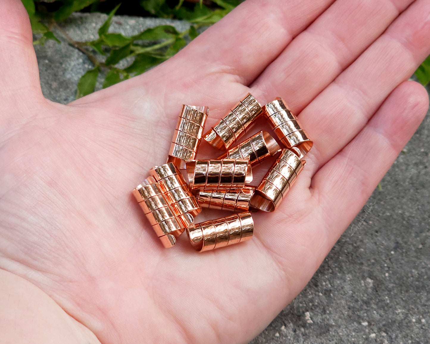 Copper hair cuffs held in hand to show scale.