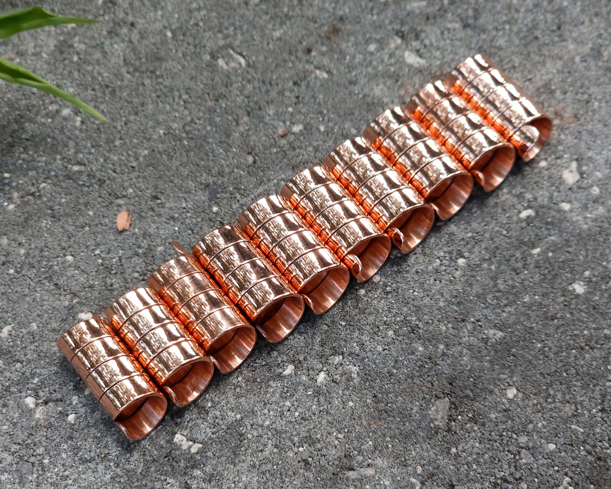 Set of 10 copper dreadlock beads on a concrete surface