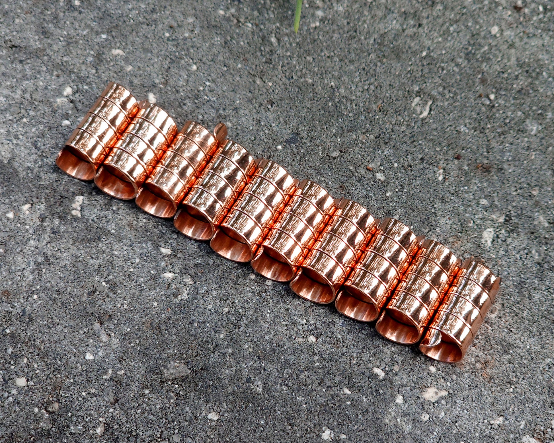 Set of 10 copper hair cuffs on a concrete surface
