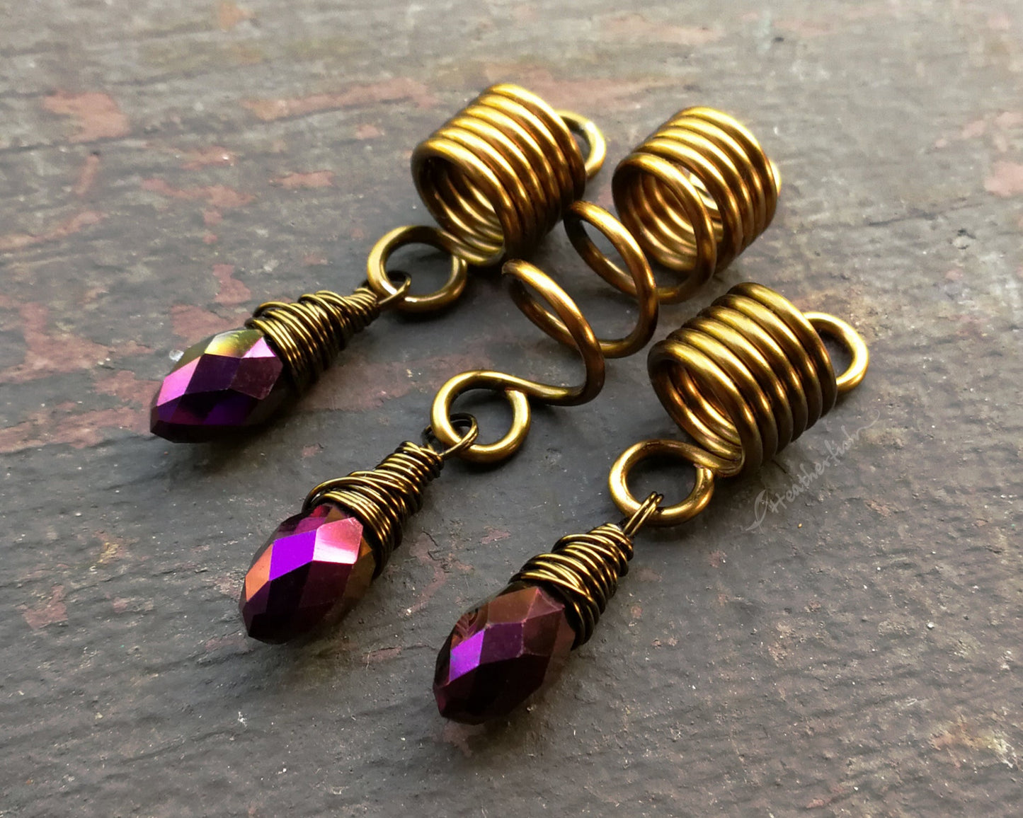 Set of 3 purple gold loc jewelry on a brown wood background.