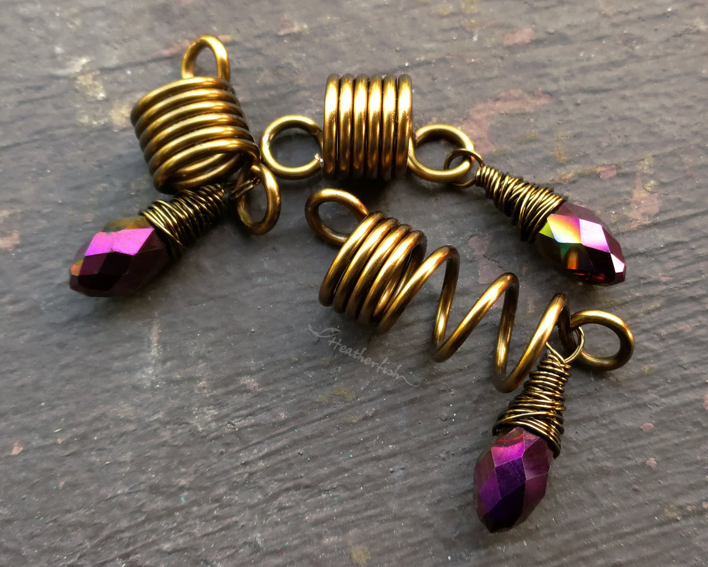 Set of 3 purple gold loc jewelry on a brown wood background.
