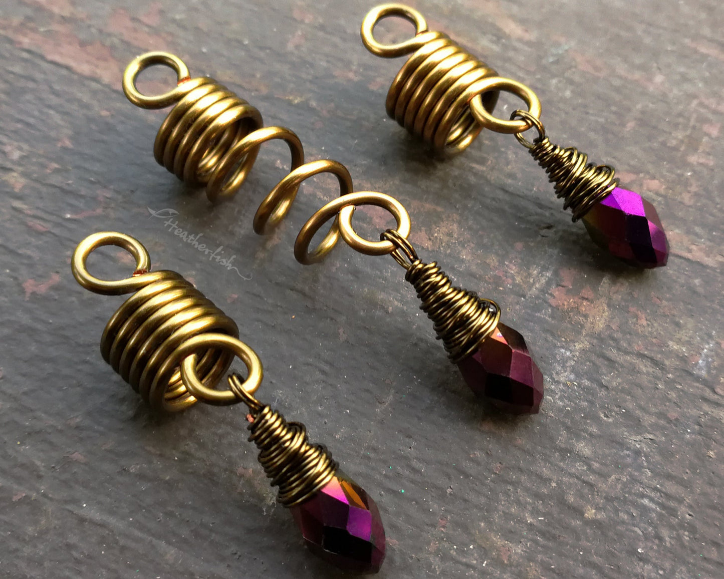 Set of 3 purple gold loc jewelry on a brown wood background.