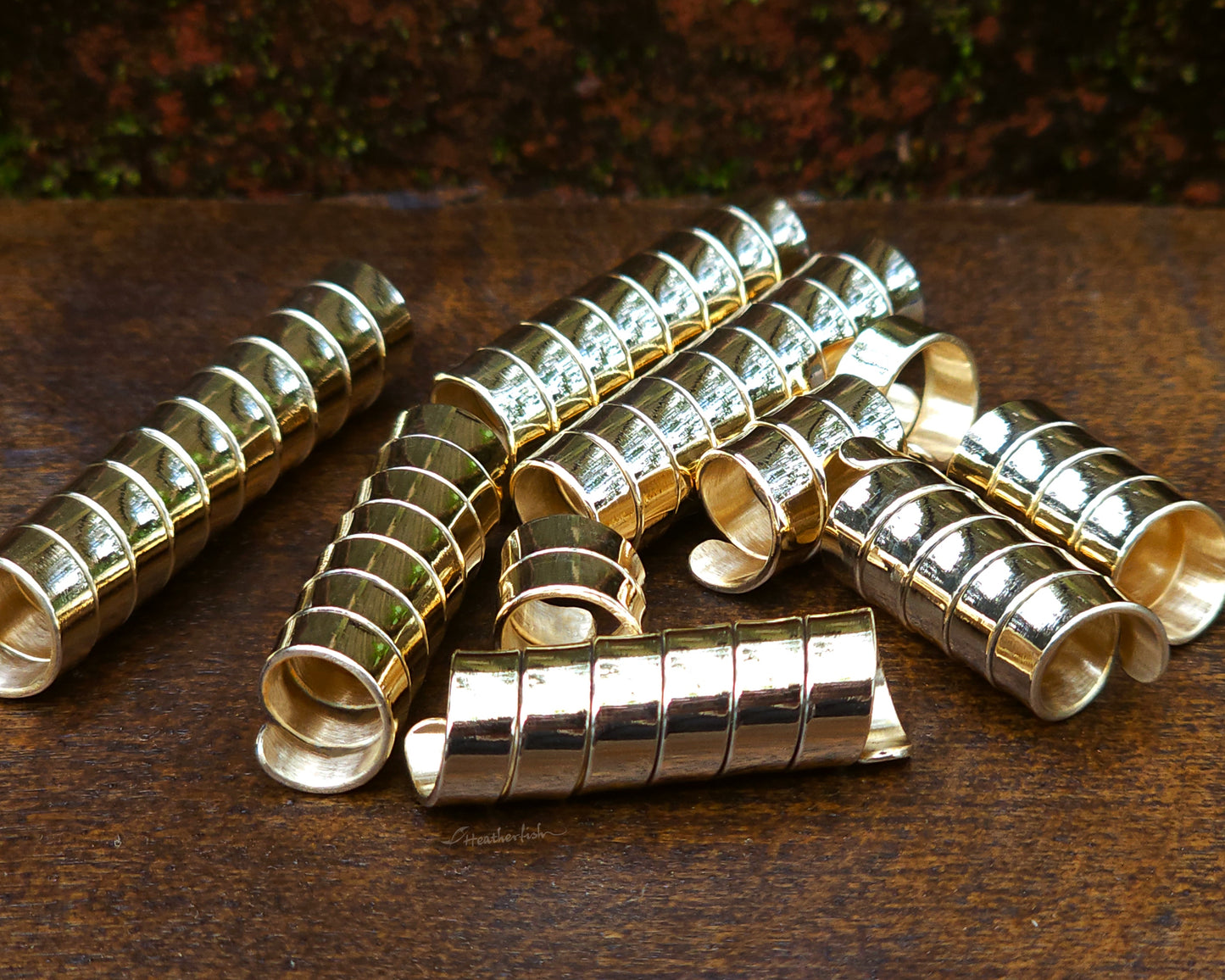 Set of 10 brass loc beads on a wood background.