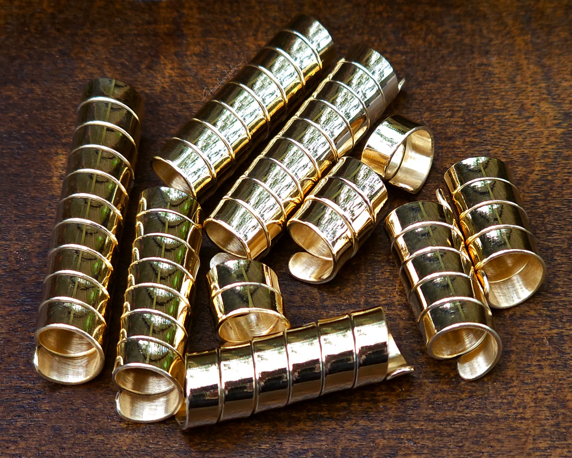 Set of 10 brass loc beads on a wood background.