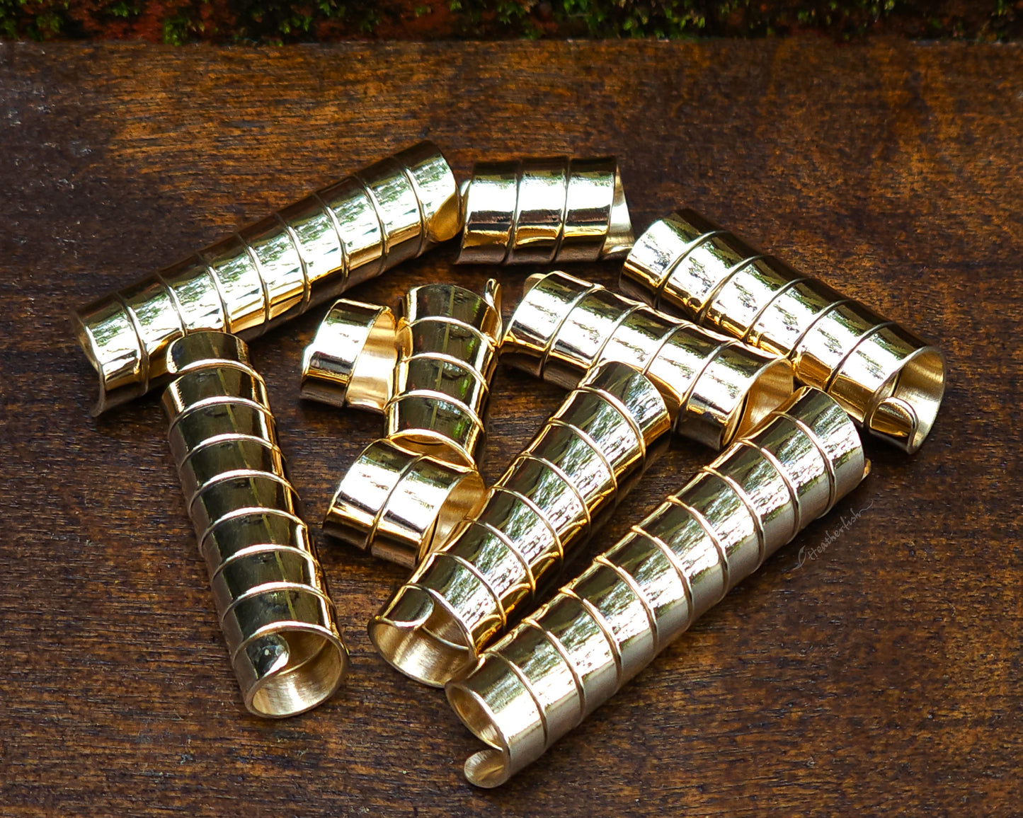 Set of 10 brass loc beads on a wood background.