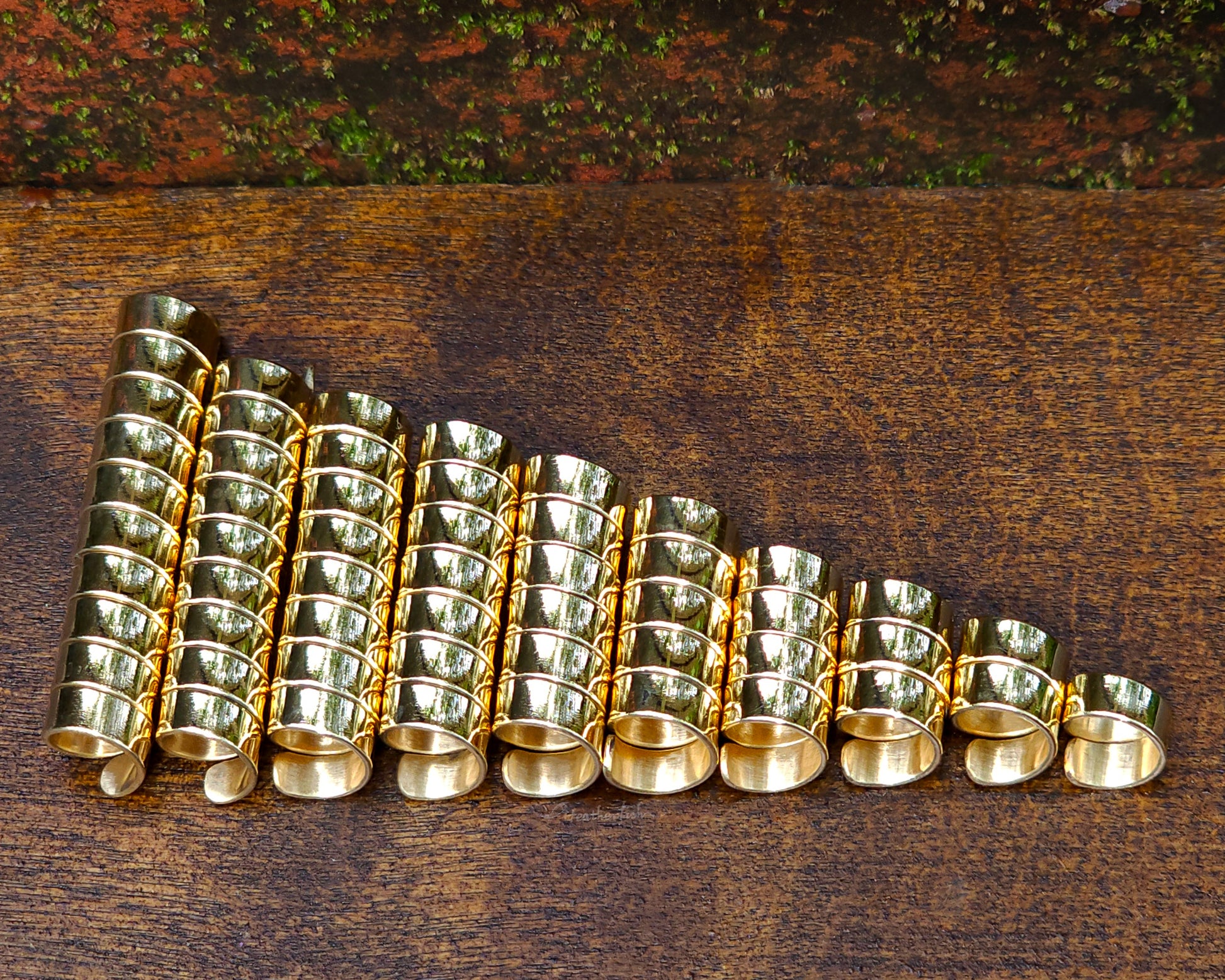 Set of 10 brass loc beads on a wood background.