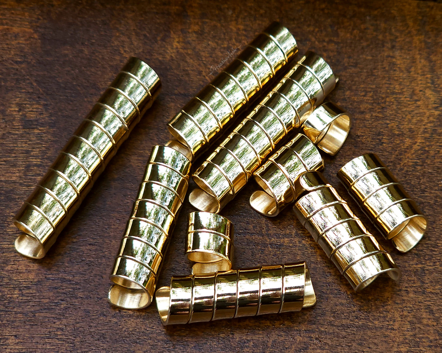 Set of 10 brass loc beads on a wood background.