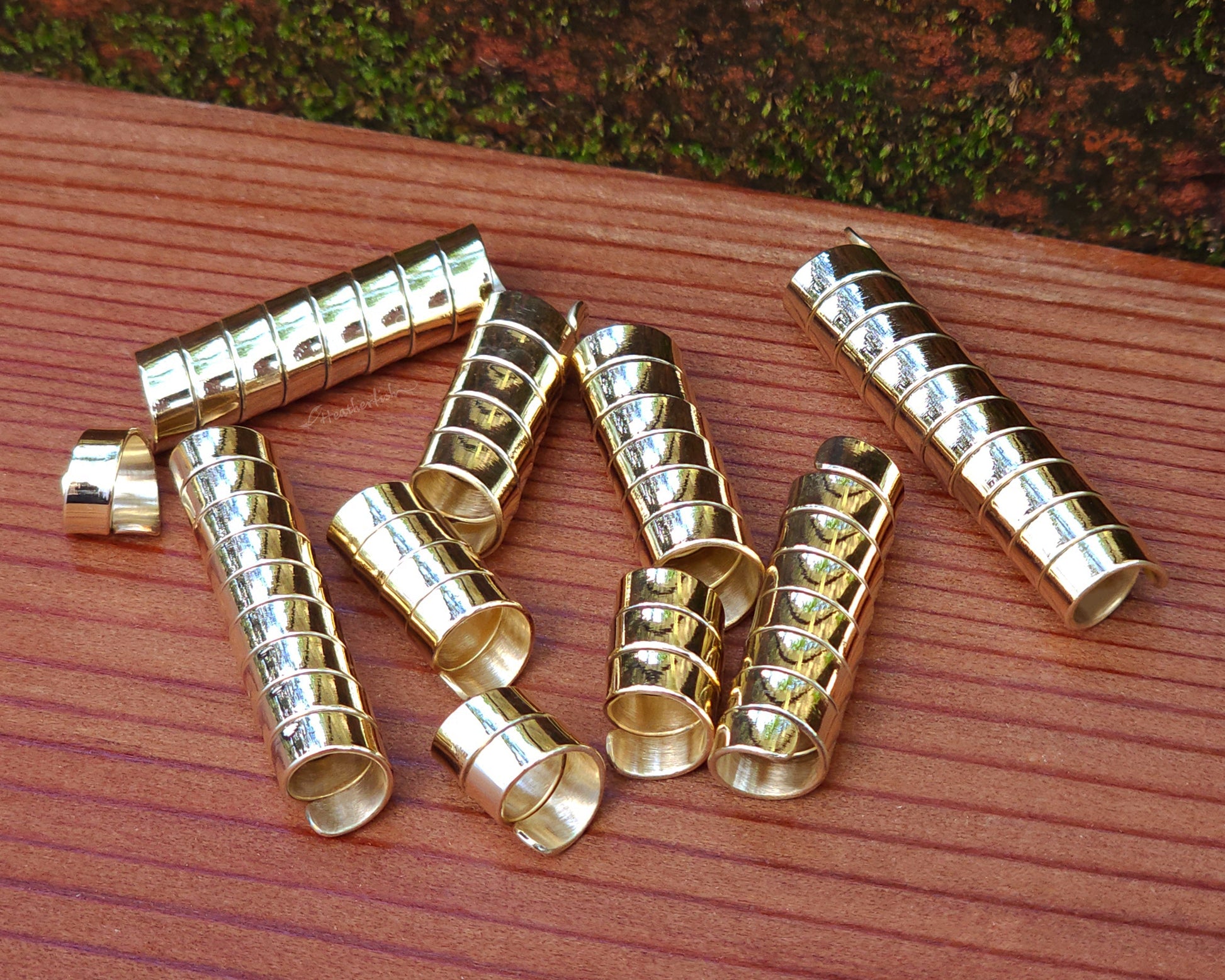 Set of 10 brass loc beads on a wood background.