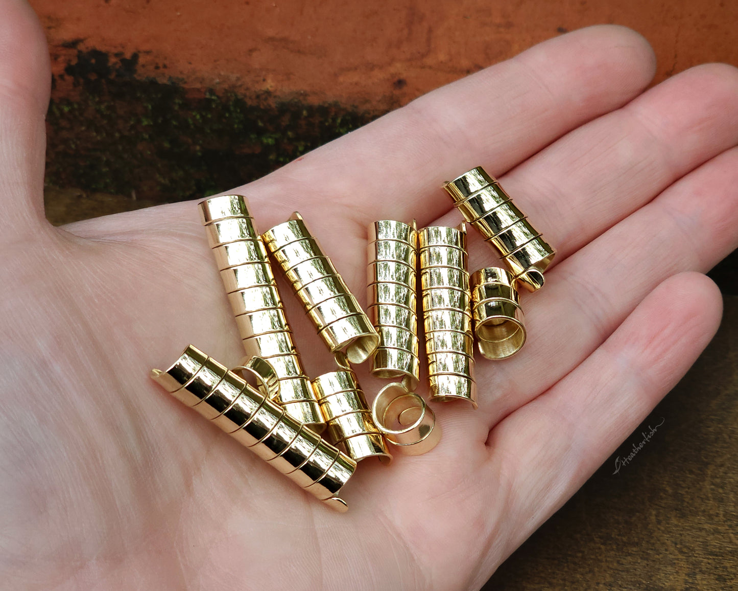 Set of 10 brass loc beads held in hand to show scale.