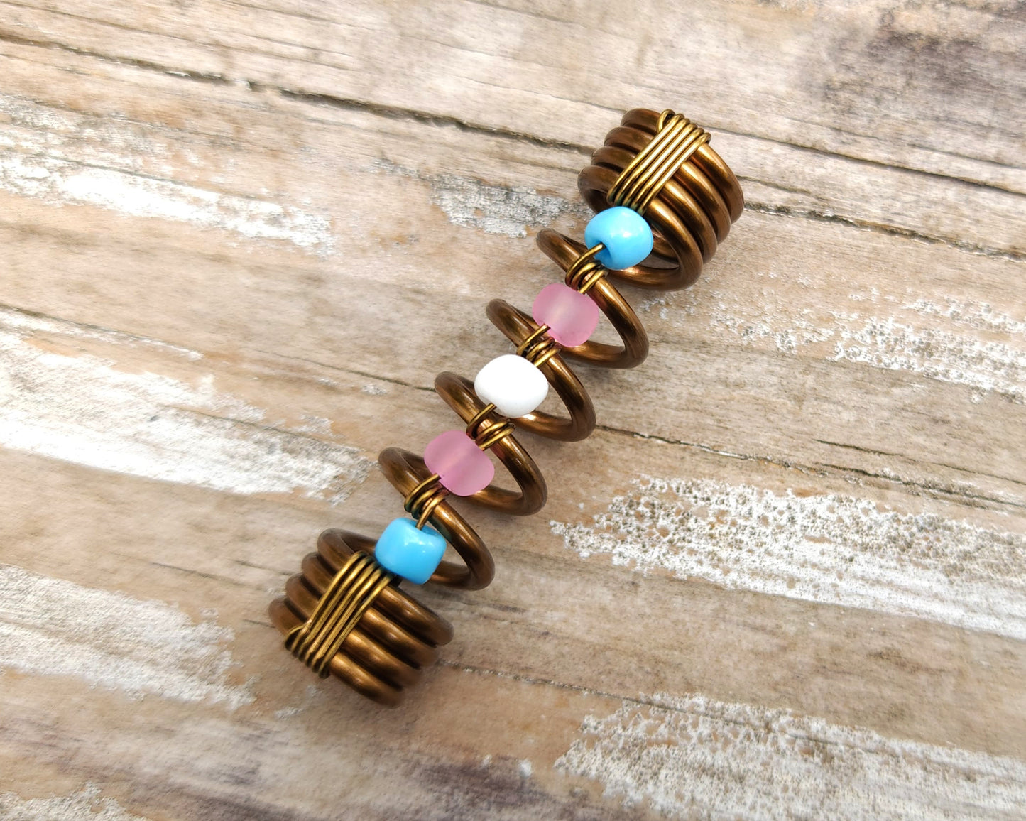 Trans pride loc bead on wood background.
