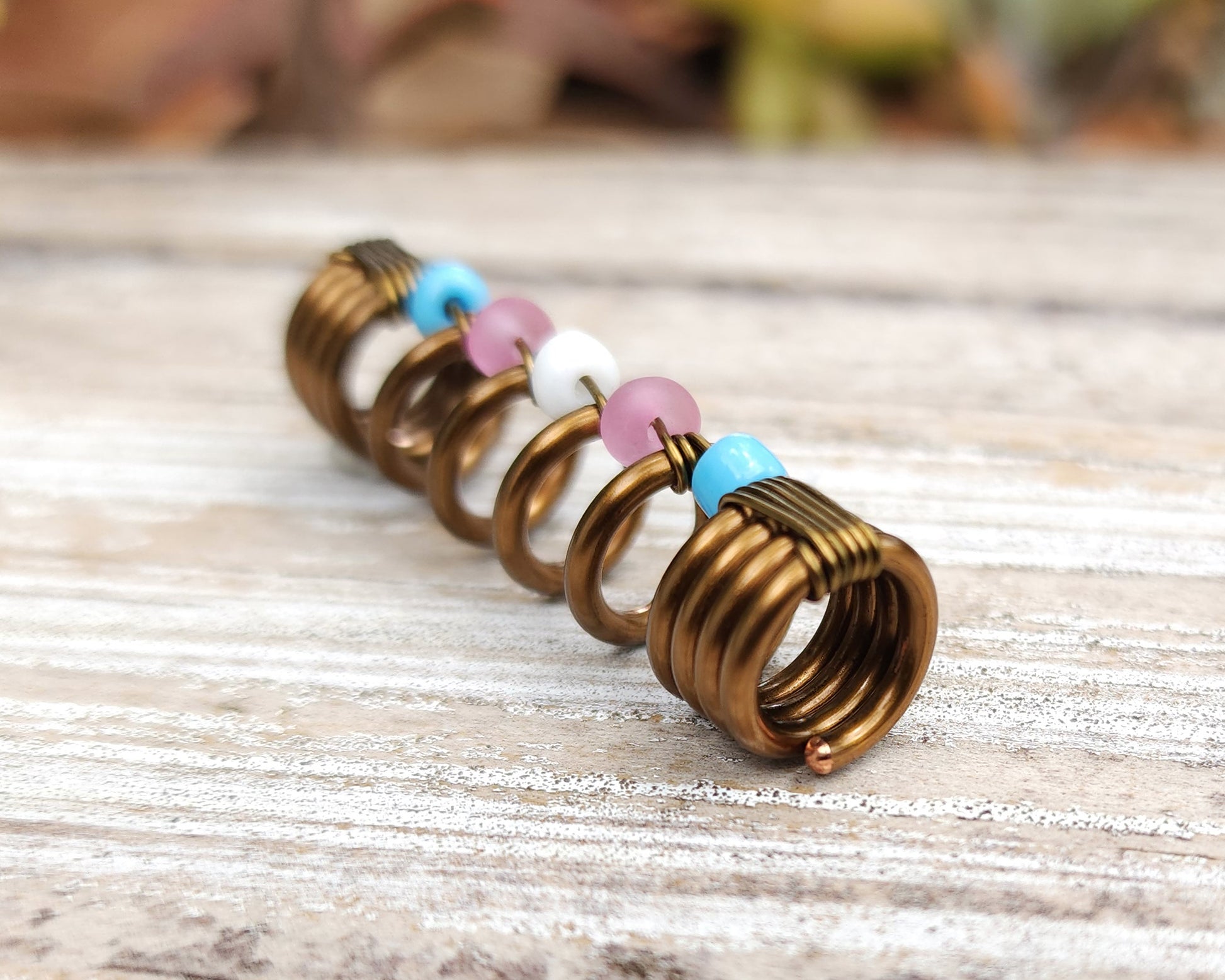Trans pride loc bead on wood background.