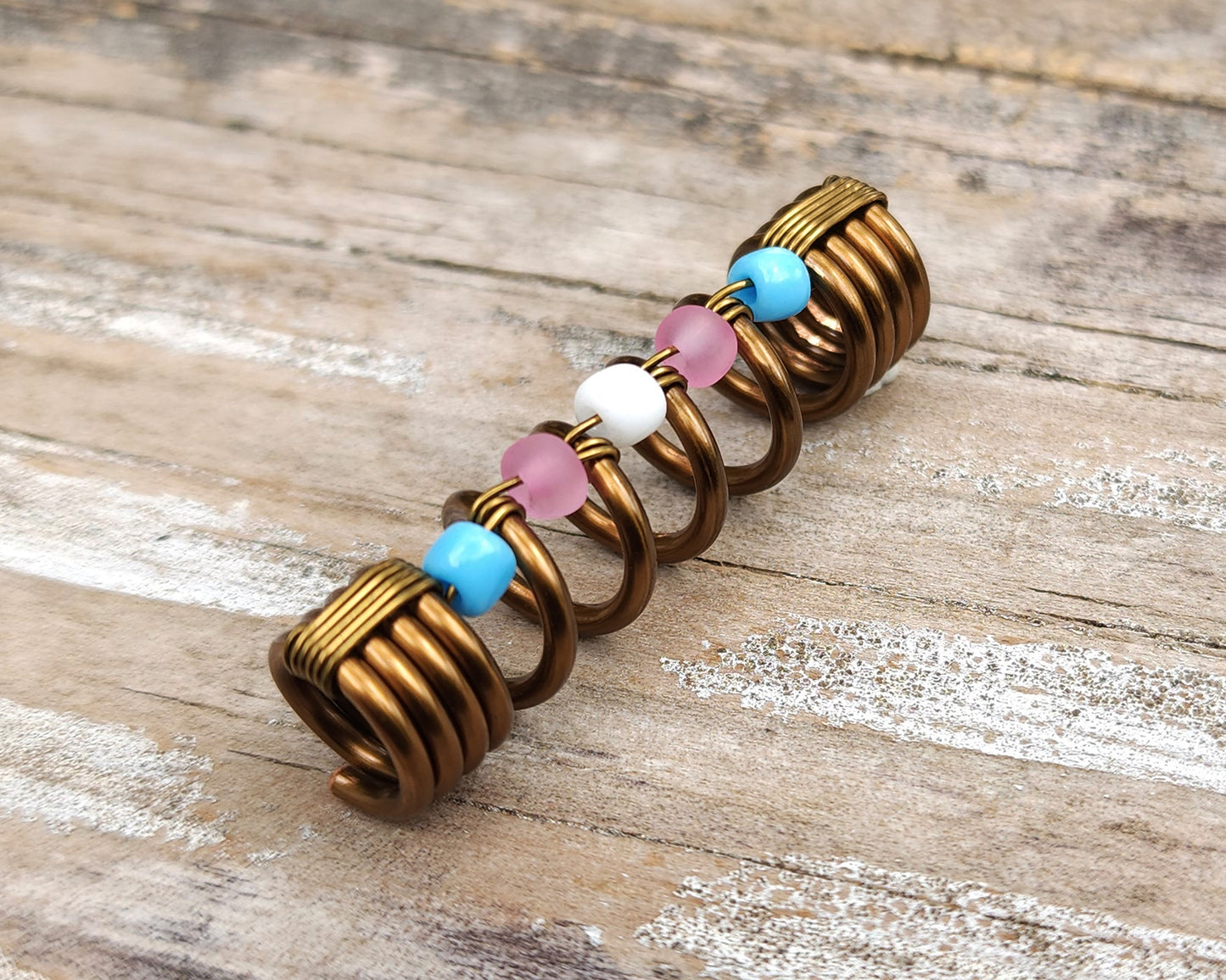 Trans pride loc bead on wood background.