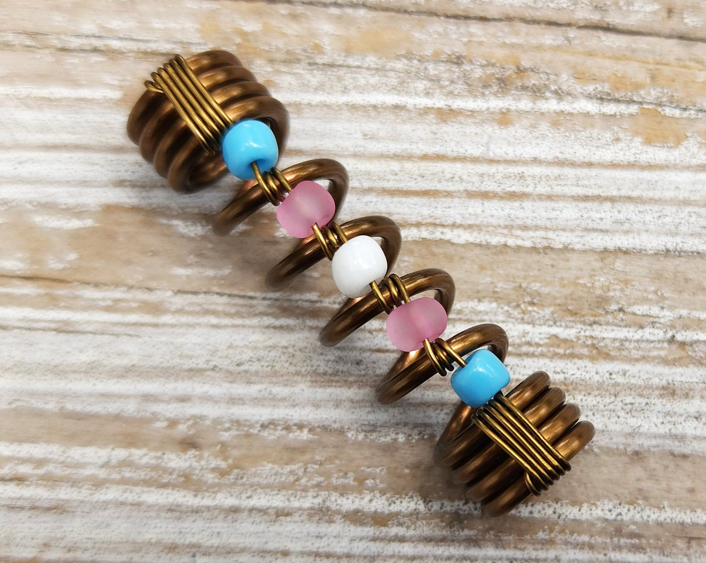 Trans pride loc bead on wood background.