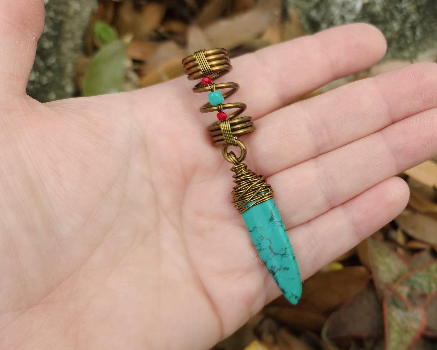 Turquoise hair jewelry held in hand to show scale.