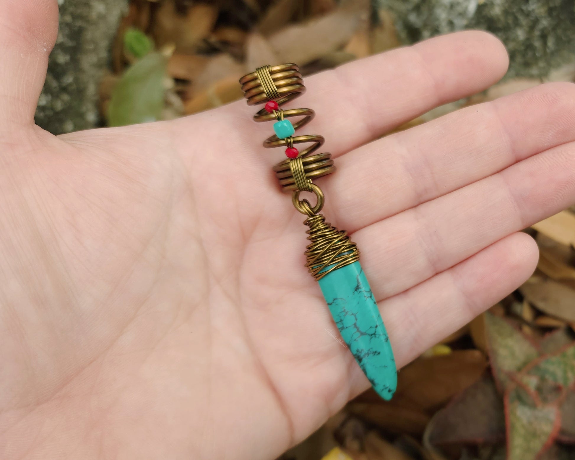 Turquoise hair jewelry held in hand to show scale.