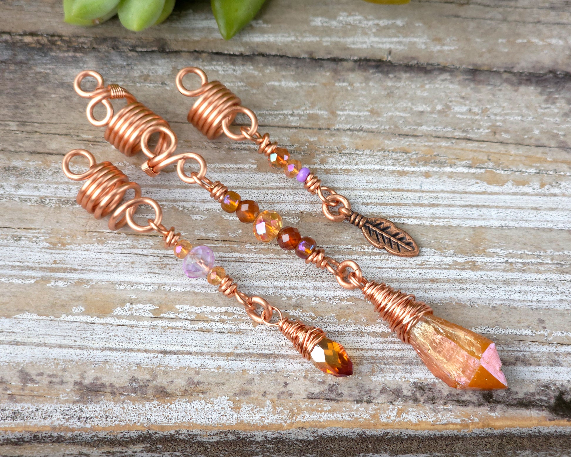 Set of three orange aura loc beads on a wood board.