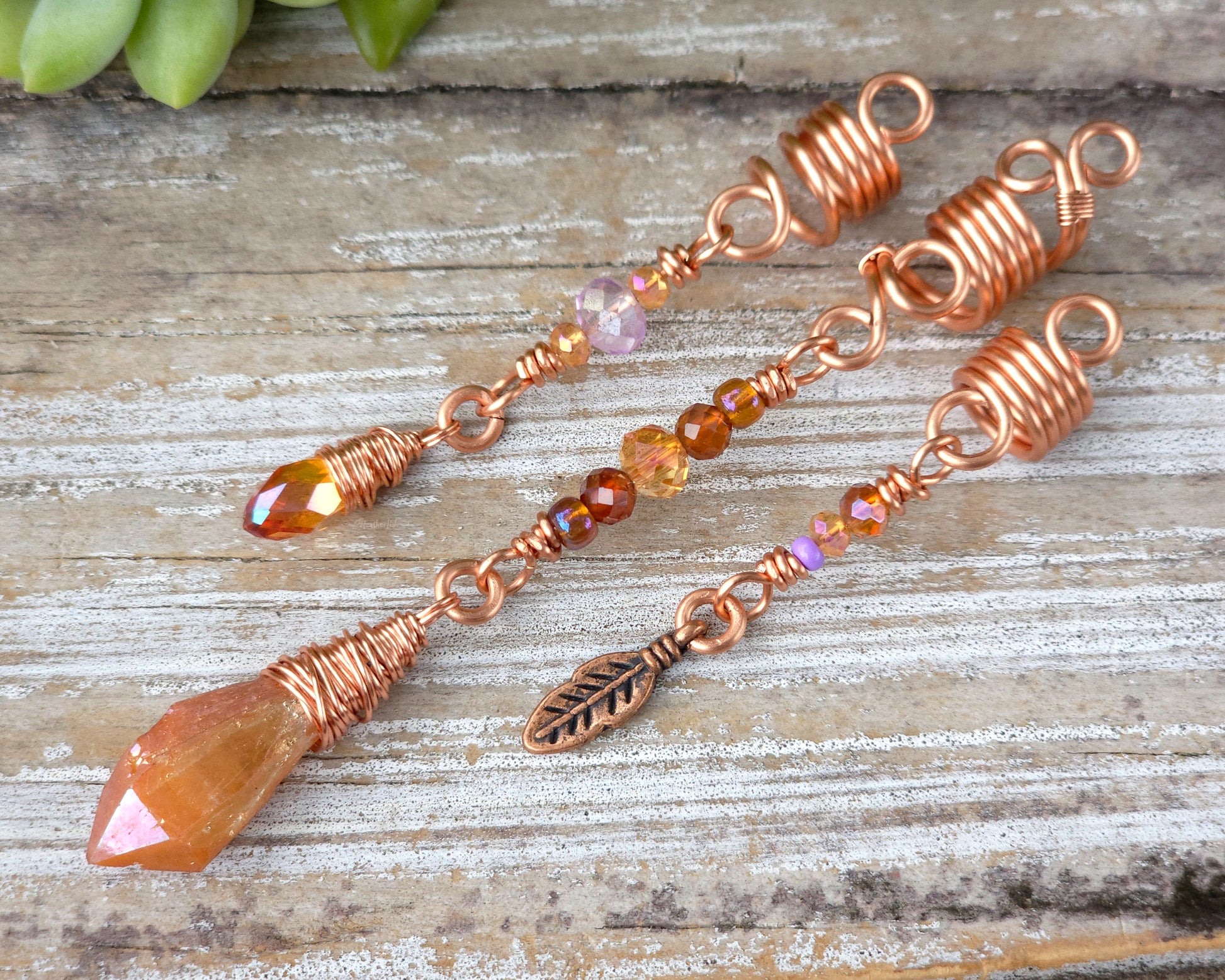 Set of three orange aura loc beads on a wood board.