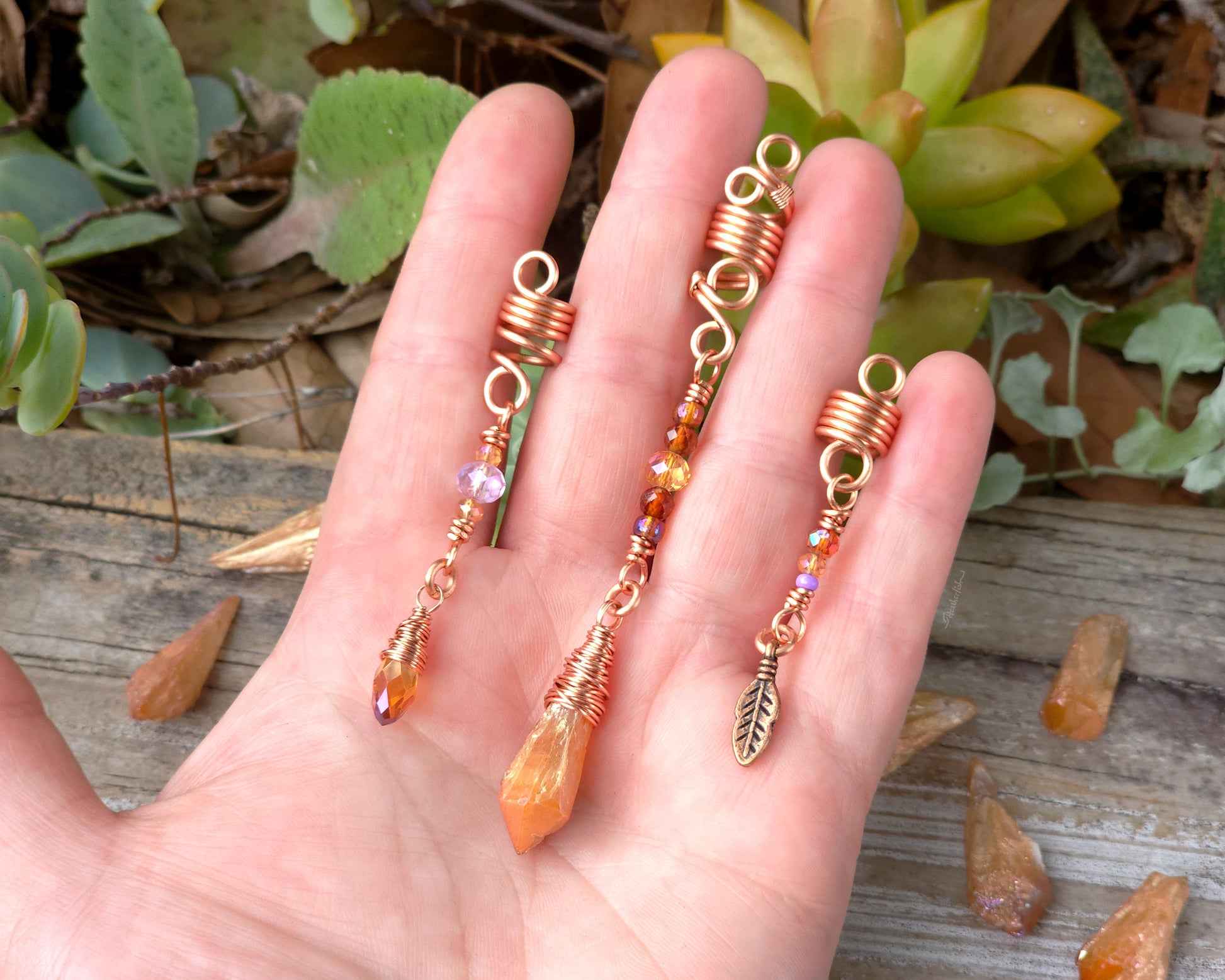Set of three orange aura loc beads held in hand to show scale.