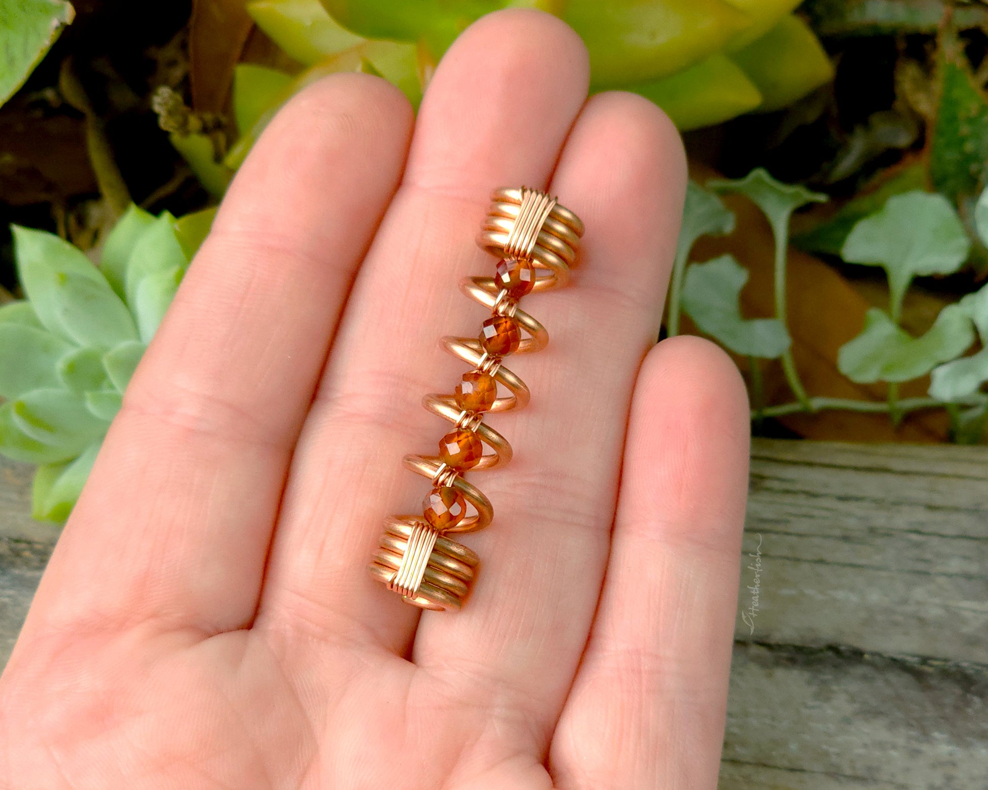 Orange garnet dreadlock bead held in hand to show scale.