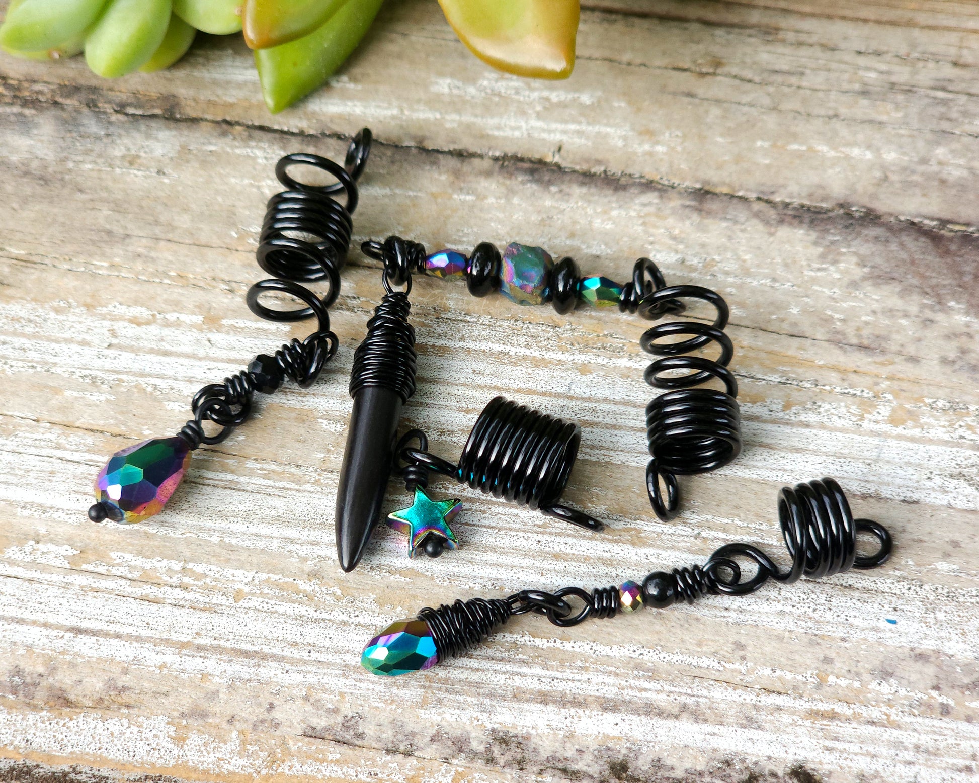 Black rainbow set of 4 dread beads on a wood board.