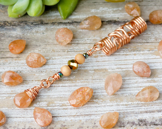 Sunstone squiggle dreadlock bead on a wood board surrounded by scattered sunstones.
