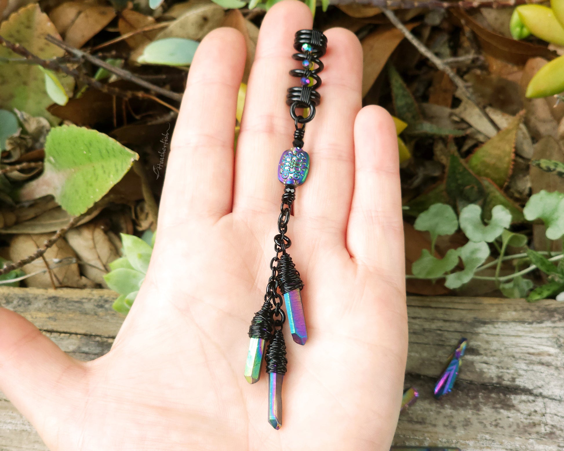 Triple rainbow titanium quartz dreadlock bead held in a hand to show scale.
