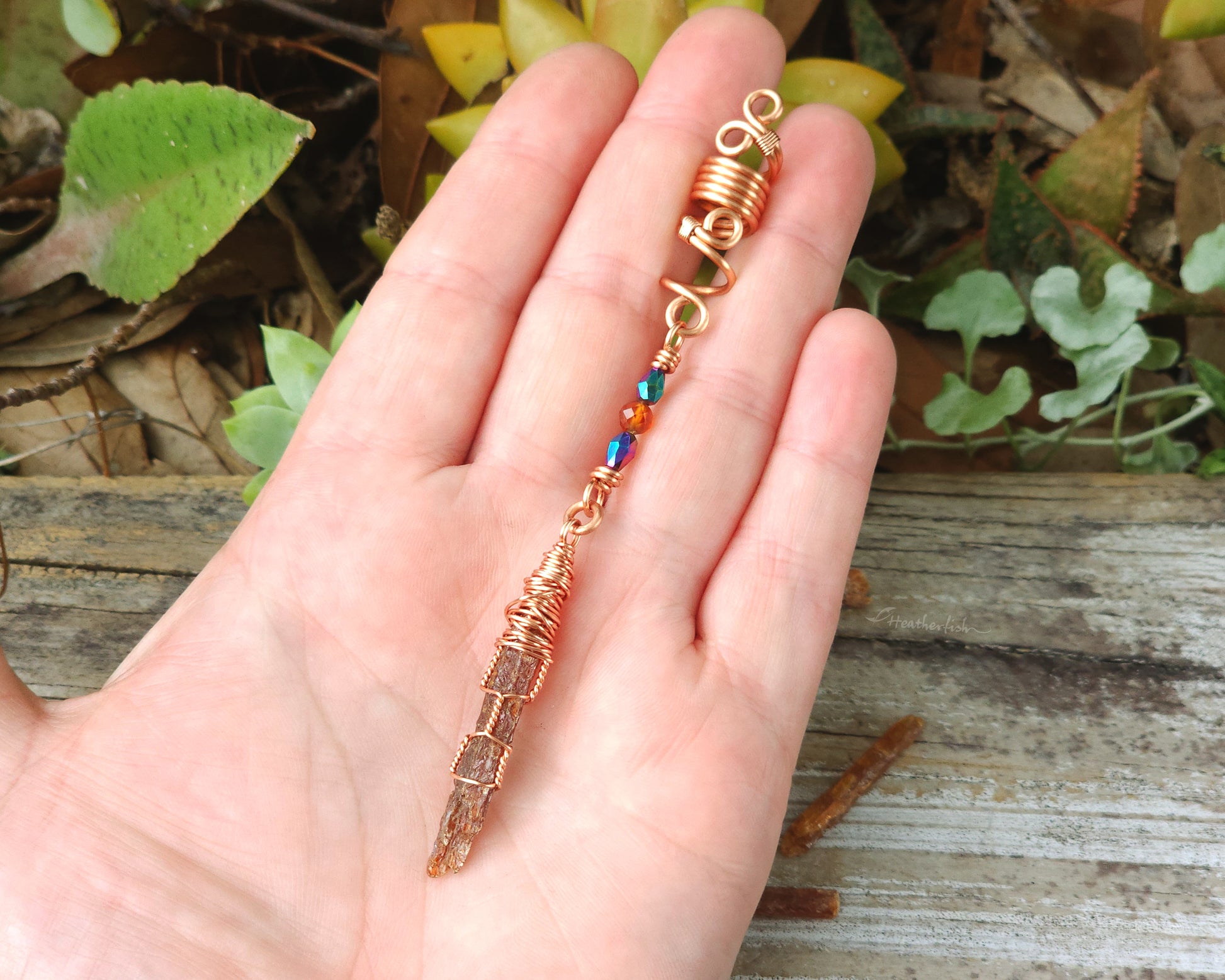 Mini orange kyanite hair bead held in hand to show scale.