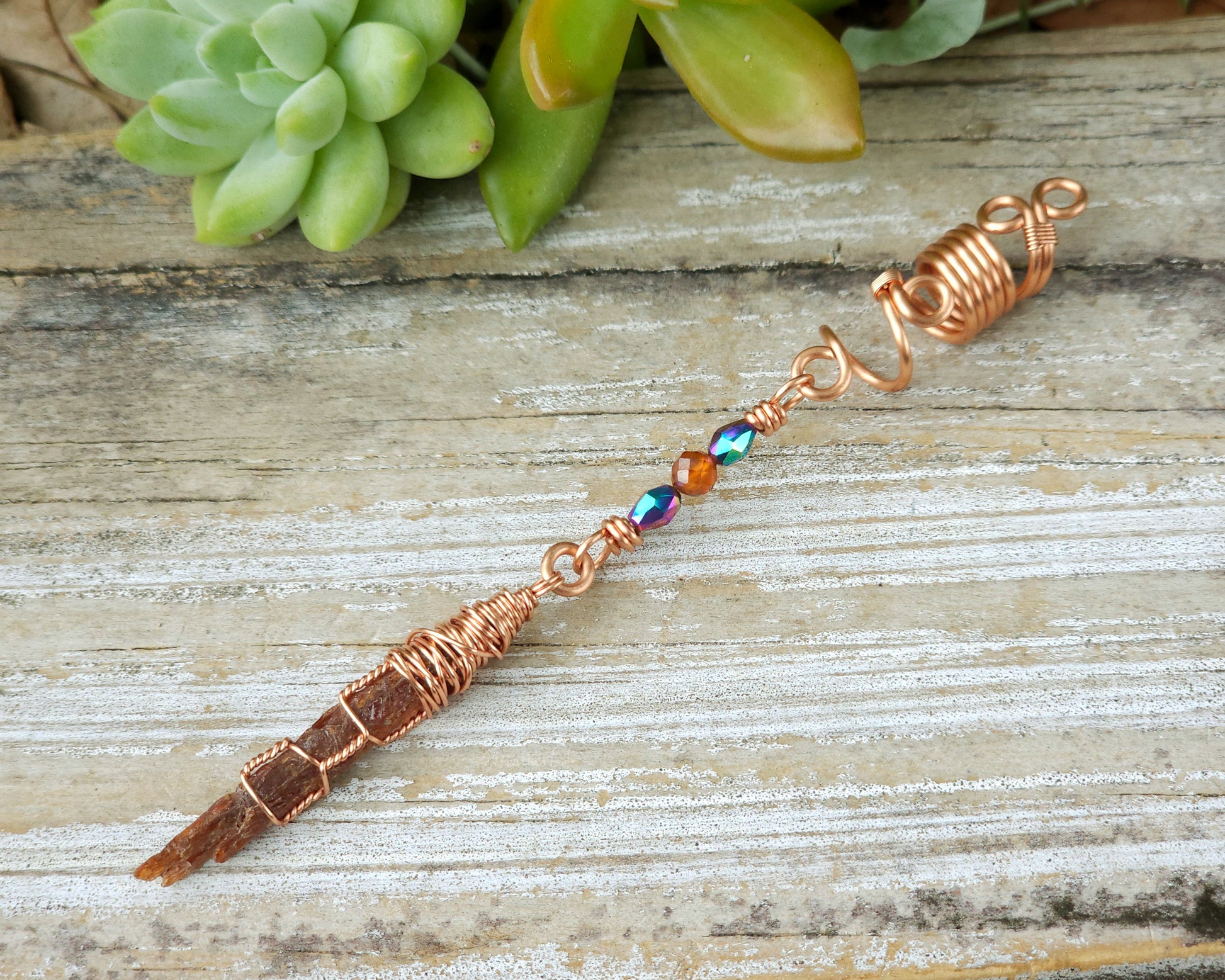 Mini orange kyanite hair bead on a wood board.