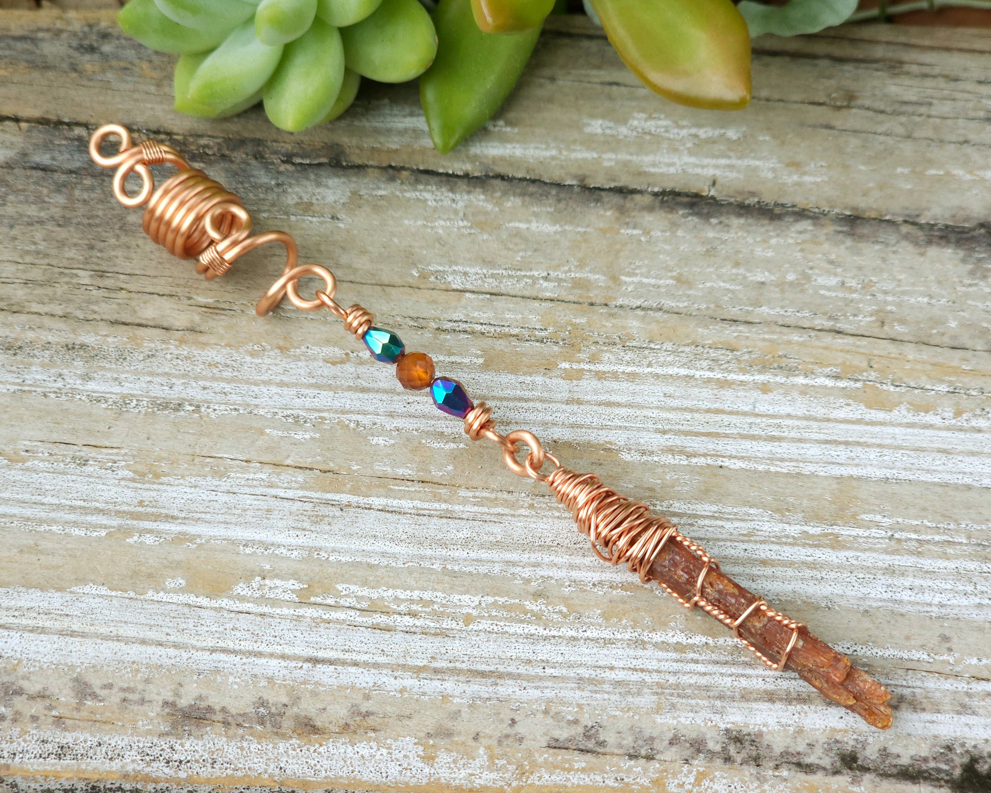 Mini orange kyanite hair bead on a wood board.