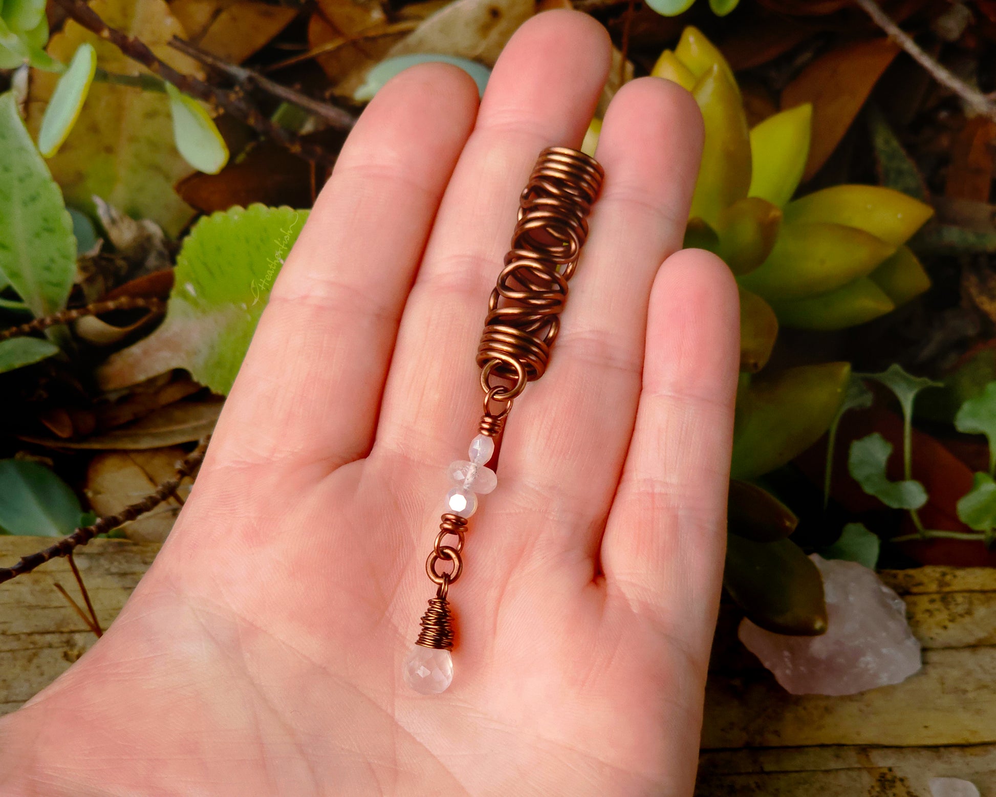 Rose quartz squiggle dreadlock bead held in hand to show scale.