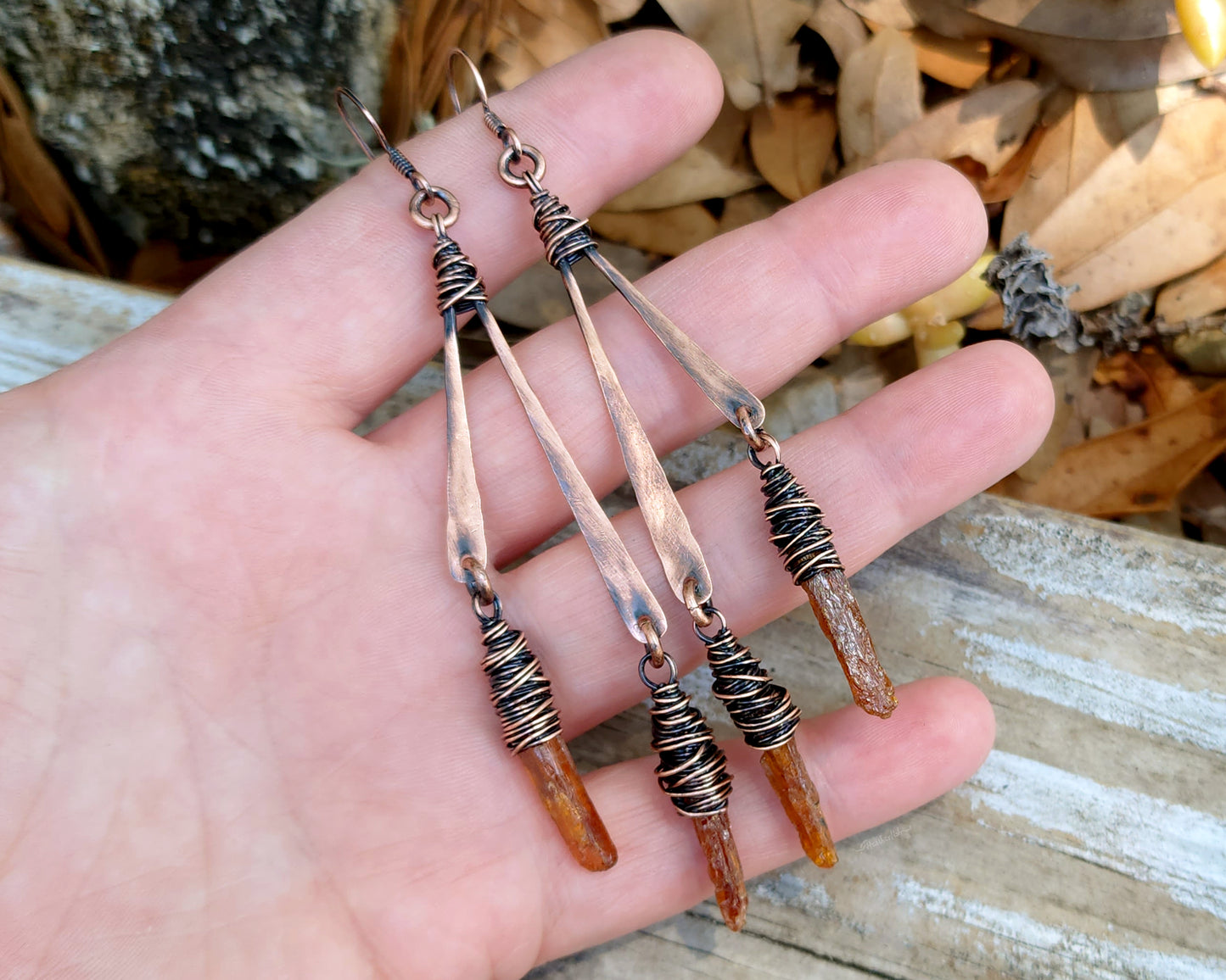 Orange kyanite earrings held in hand to show scale.