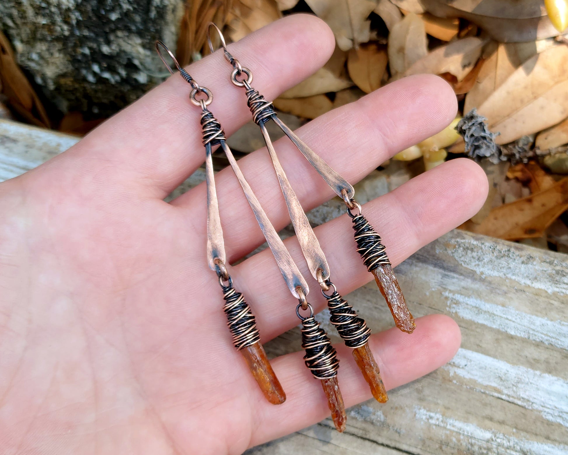 Orange kyanite earrings held in hand to show scale.