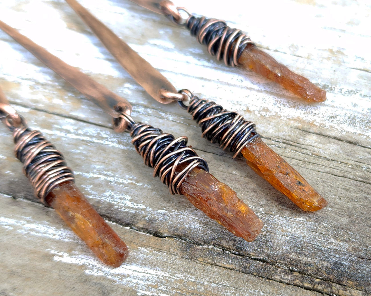 Orange kyanite earrings on a wood background.