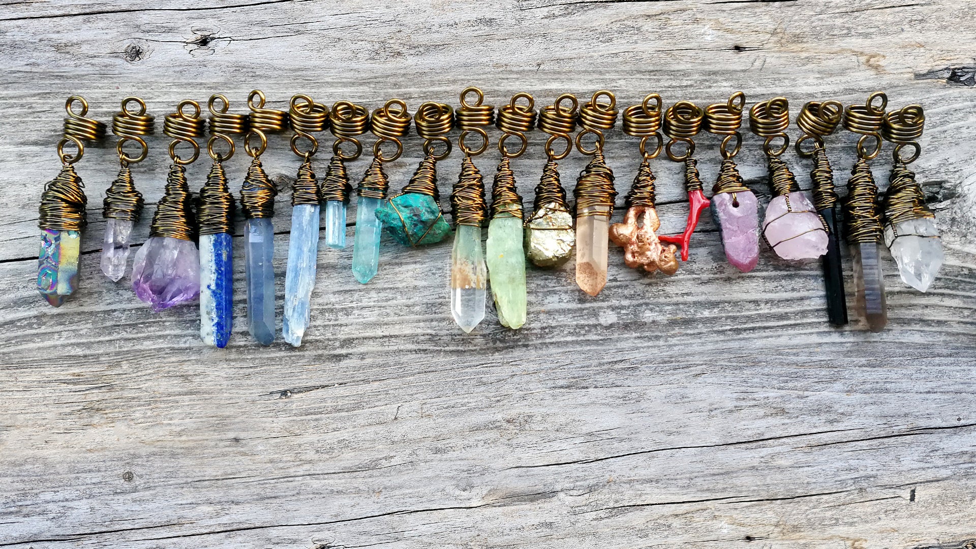 Hair beads lined up in a row with an array of different color minerals in rainbow order on a wood background.