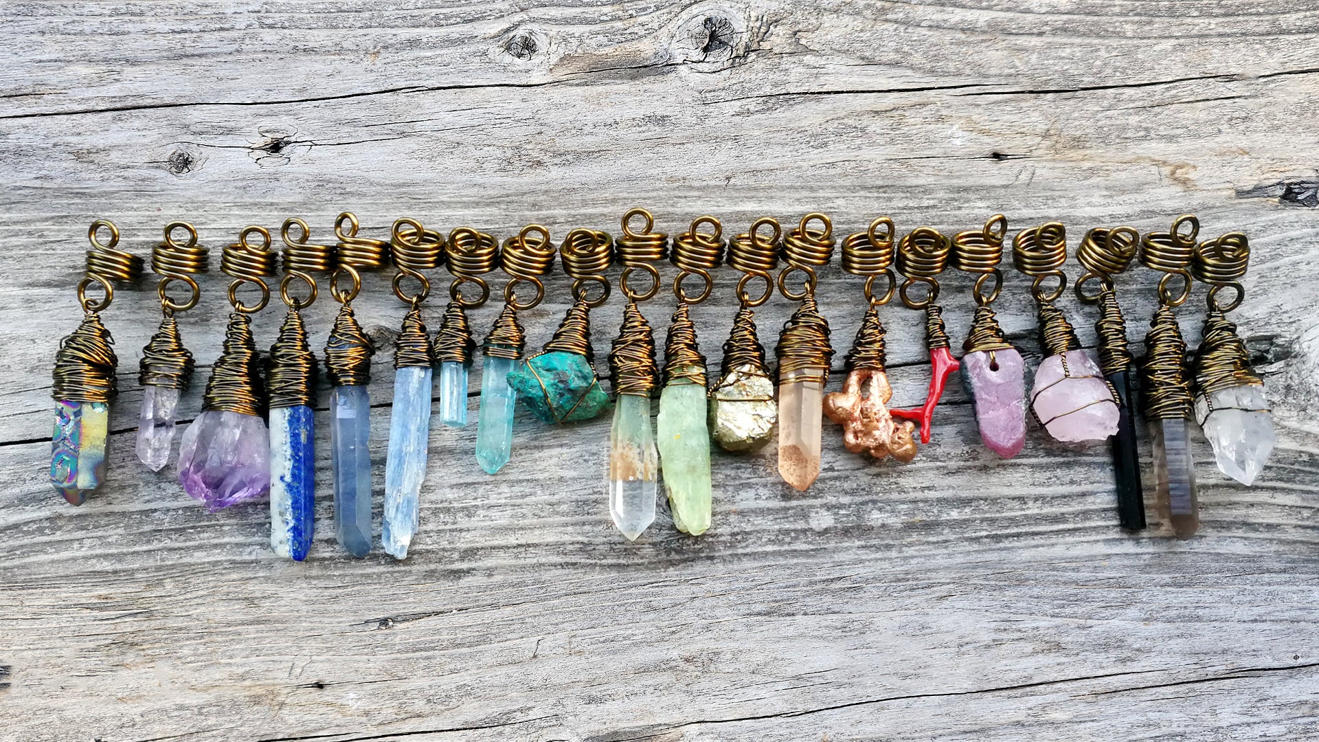 Hair beads lined up in a row with an array of different color minerals in rainbow order on a wood background.