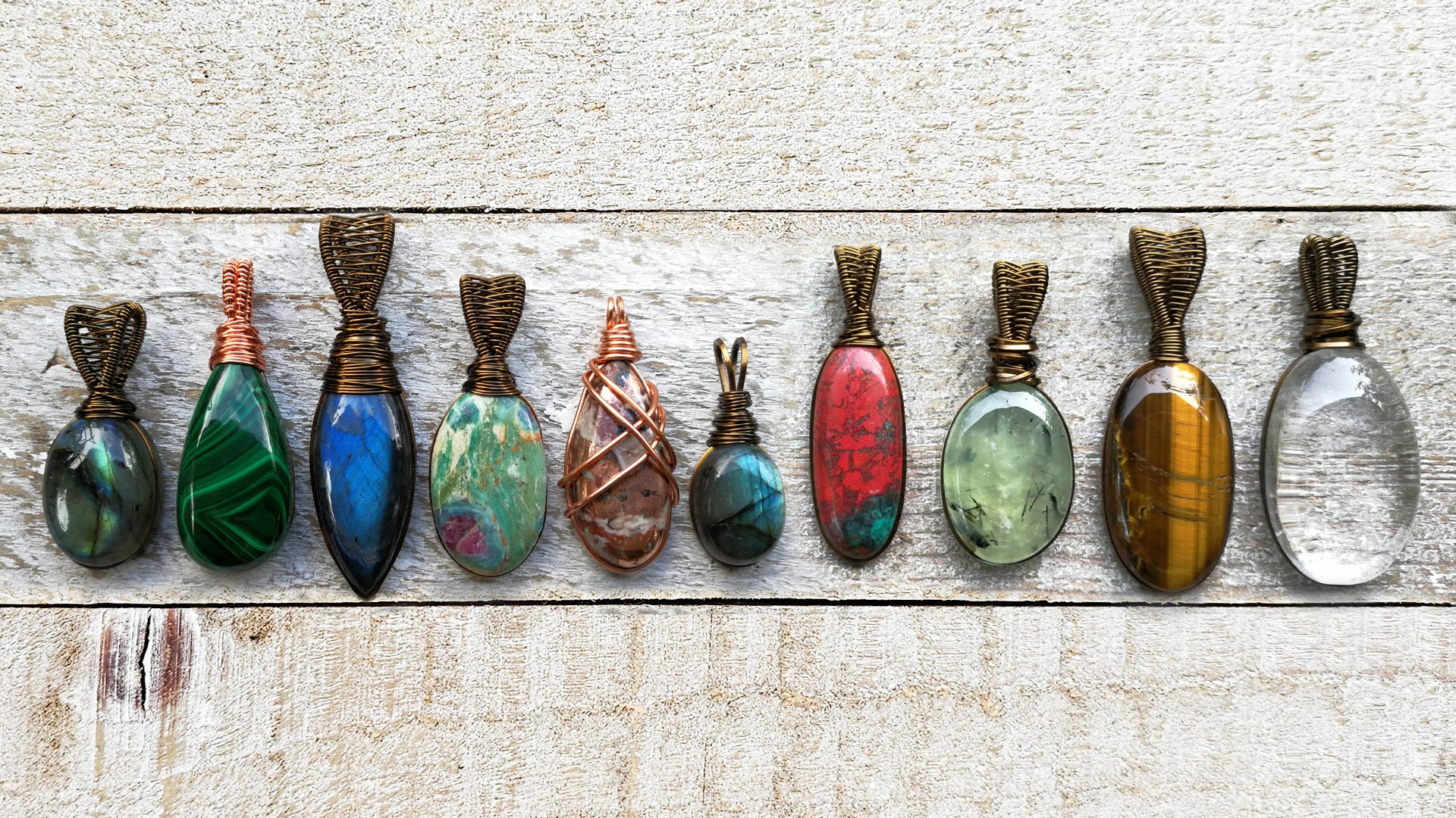 Banner image of multiple stone pendants on a white wood background.