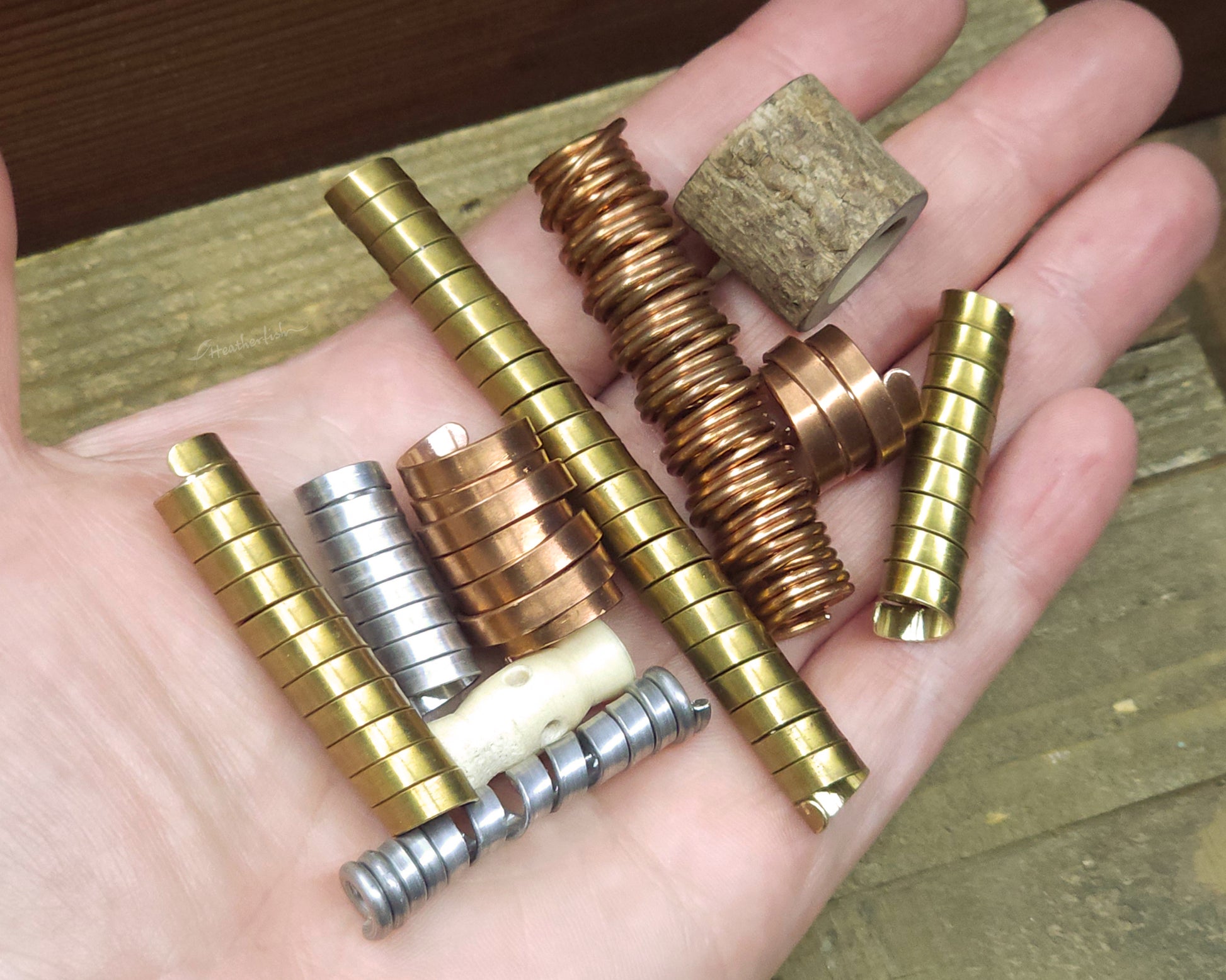 Collection of various dreadlock beads held in hand to show scale.