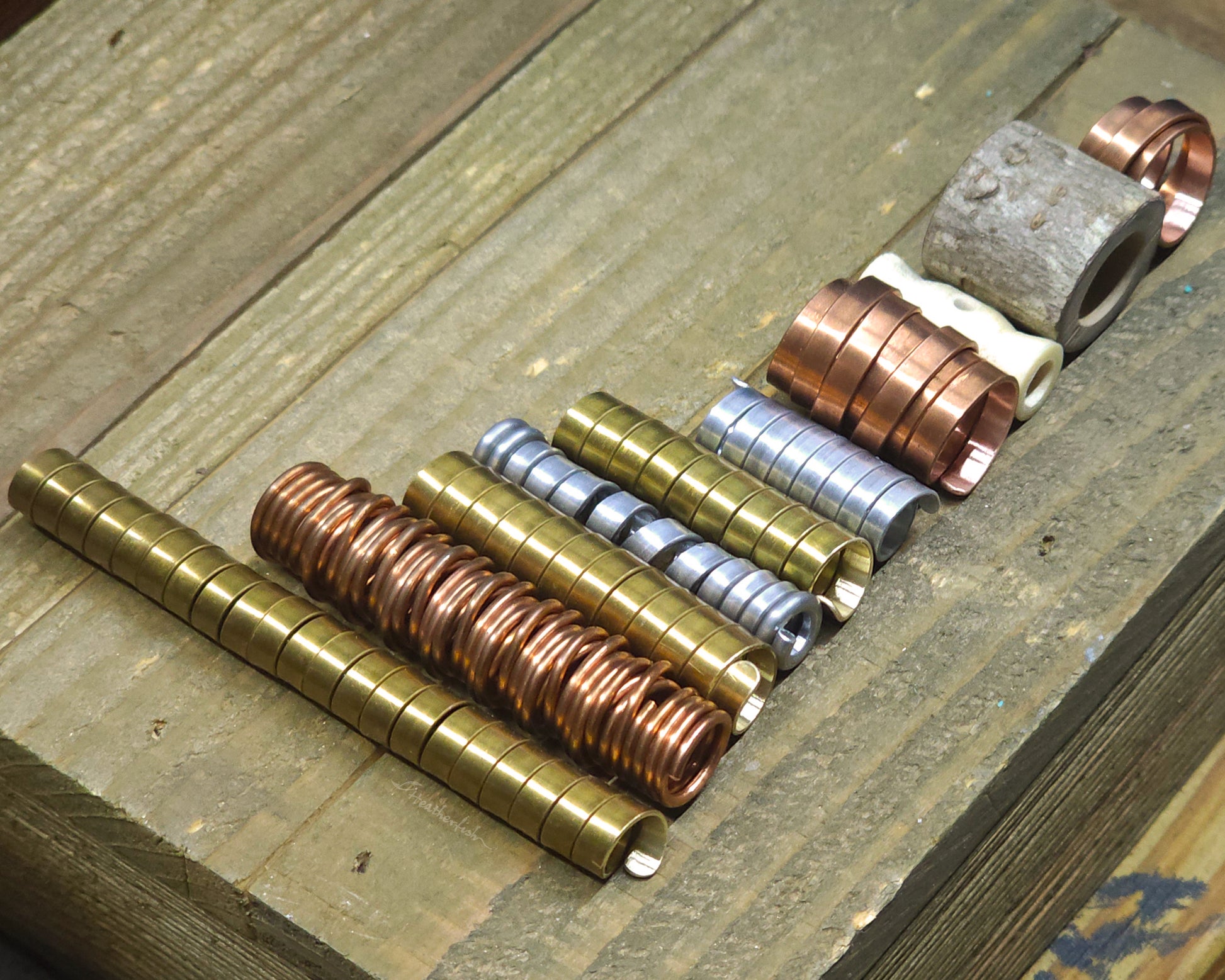 Collection of various dreadlock beads against a wood surface.