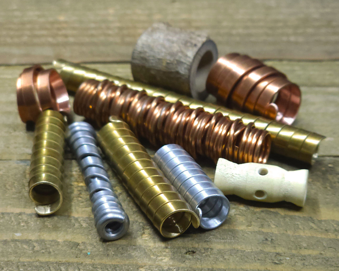 Collection of various dreadlock beads against a wood surface.