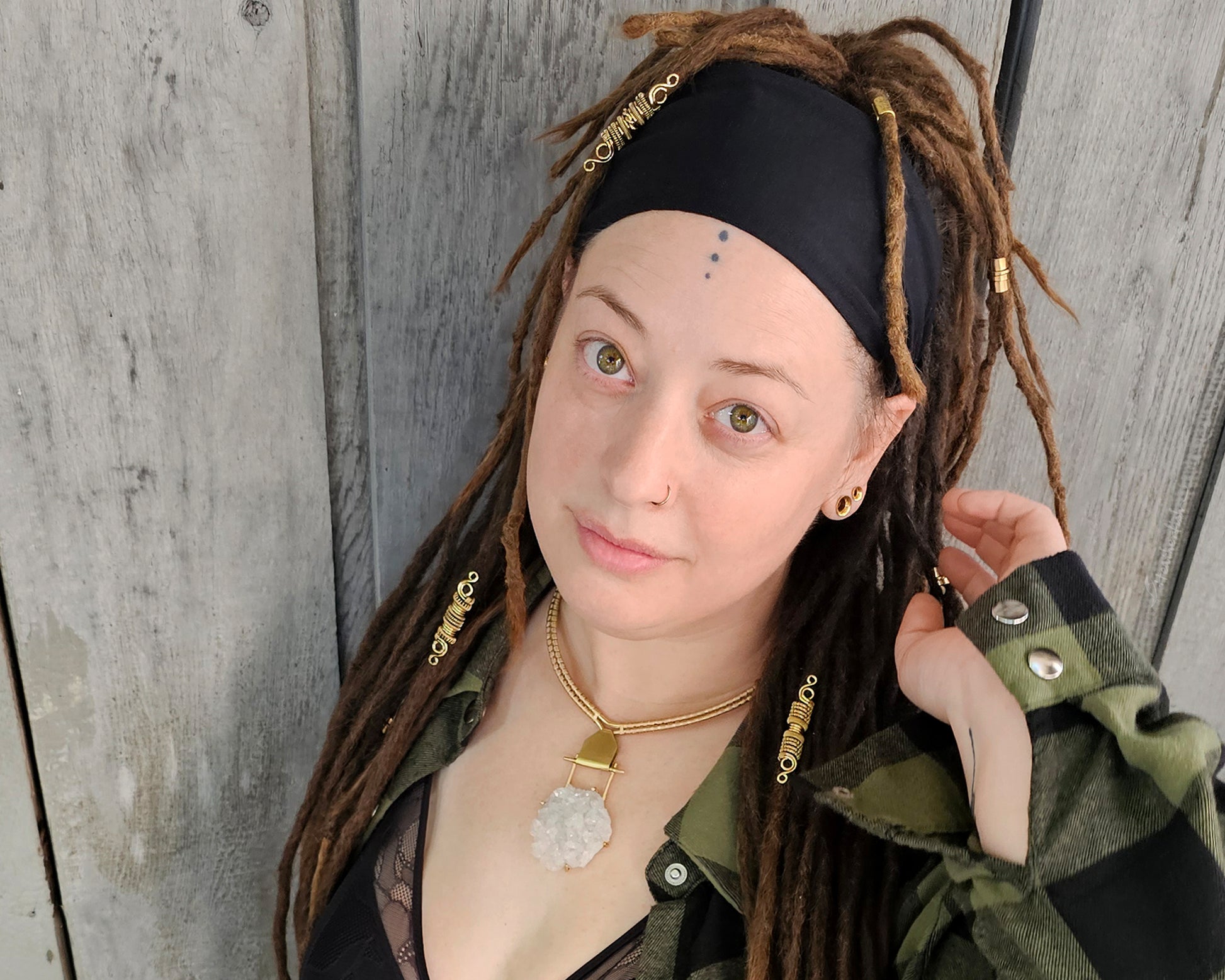 Artist Heather wearing a yellow brass Arkansas quartz torque necklace with green and black plaid shirt.