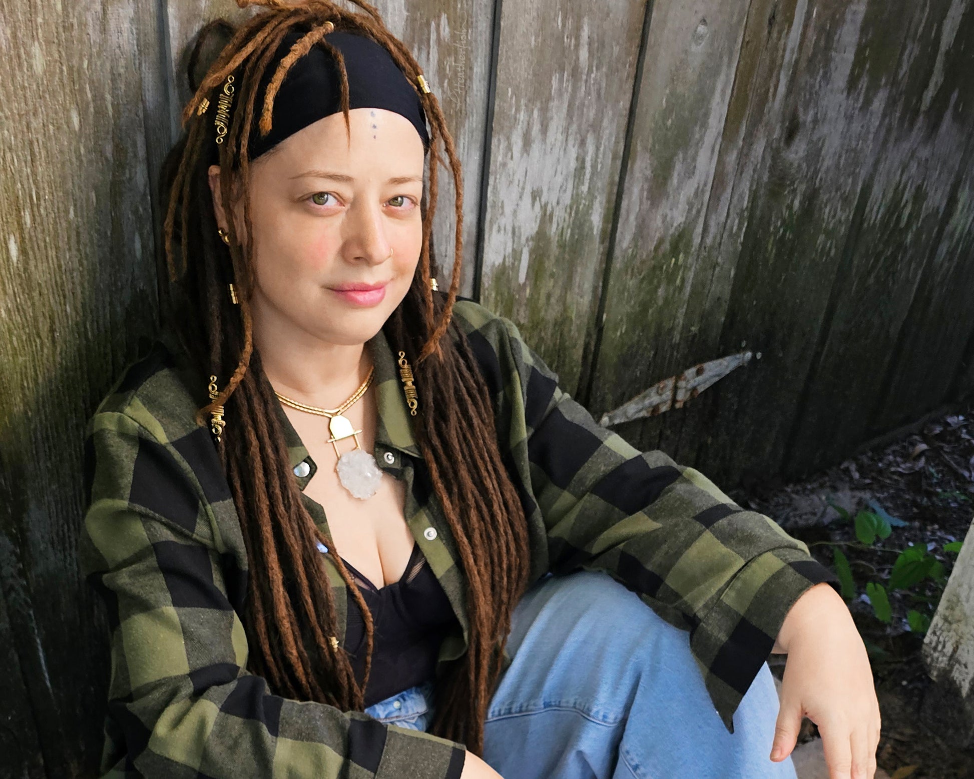 Artist Heather wearing a yellow brass Arkansas quartz torque necklace with green and black plaid shirt.