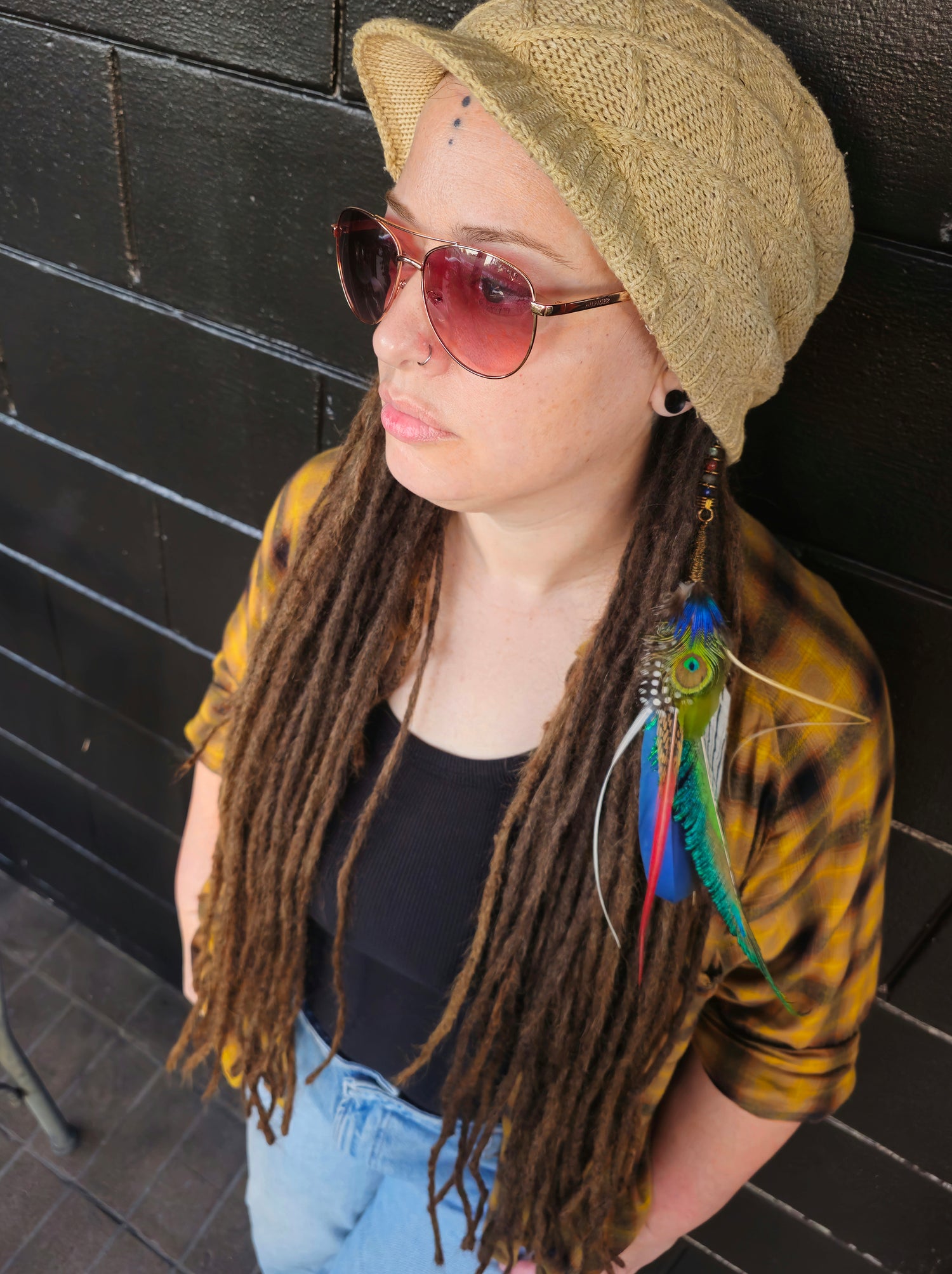 Artist and owner of heatherfish standing against a black brick wall.