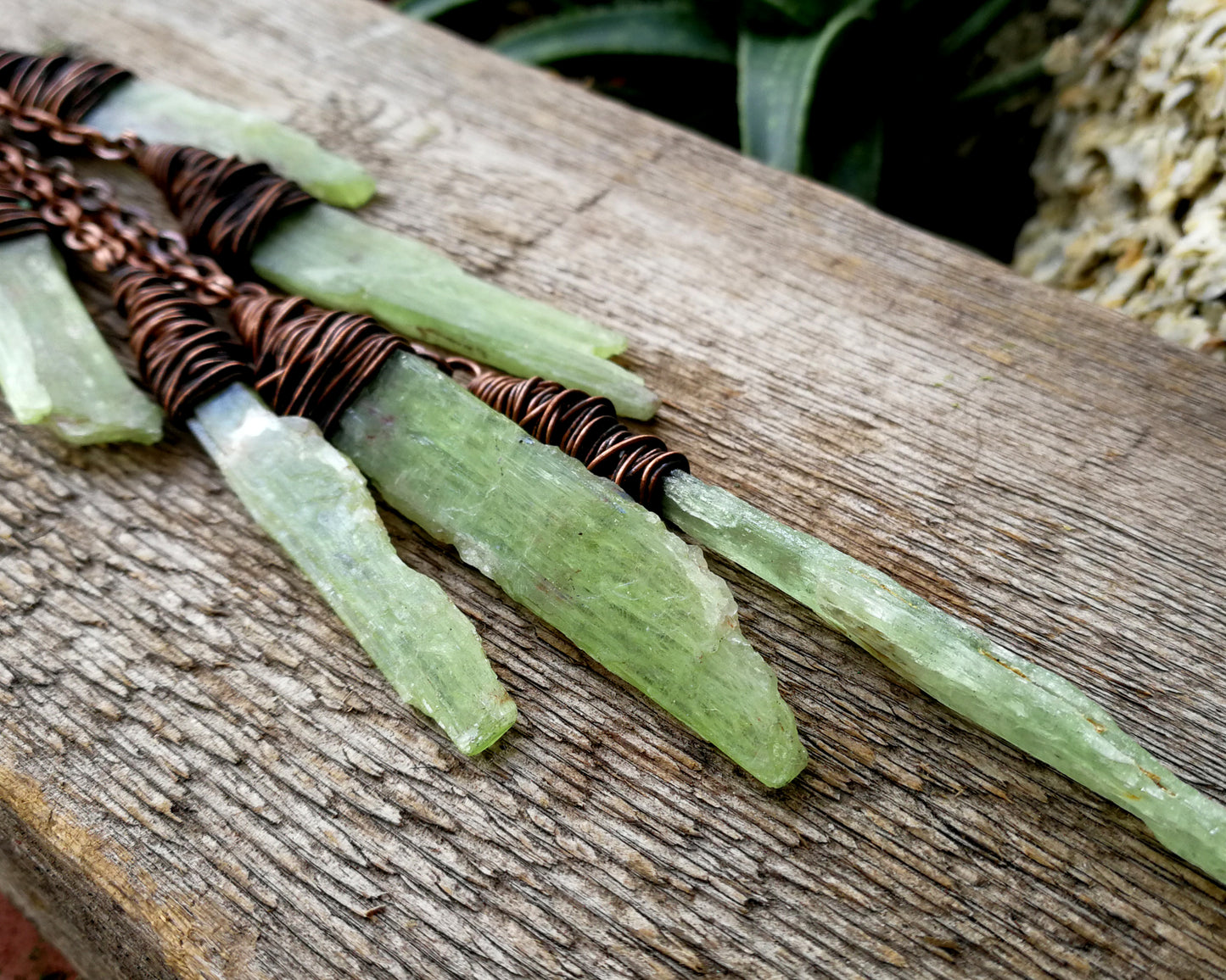 A large kyanite hair cuff on a wood board.