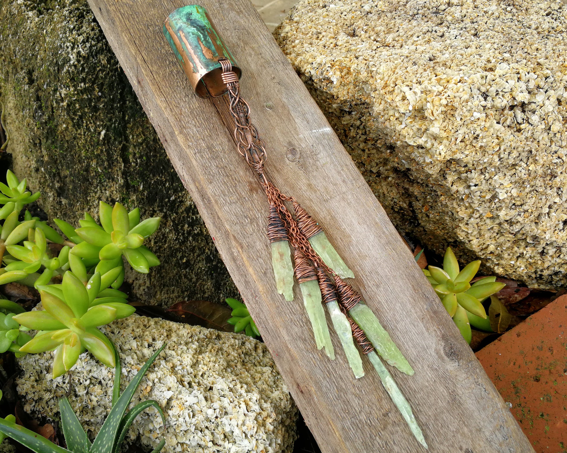 A large kyanite hair cuff on a wood board.