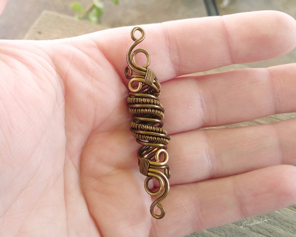 A top view of a Fancy Woven Filigree Dread Bead in hand.